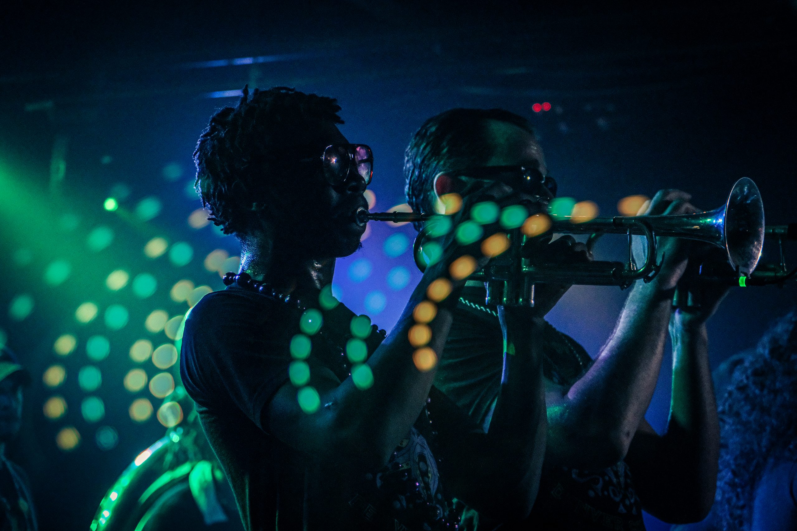 Brothers of Brass trumpet players performing under green and blue stage lights